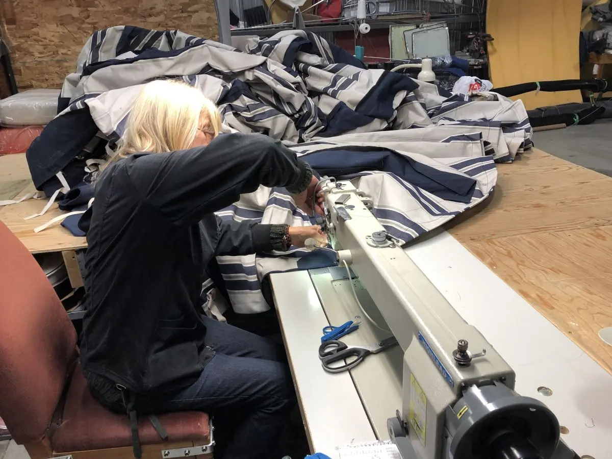 Artisane cousant à la machine une grande toile rayée dans l’atelier Redecor Plus