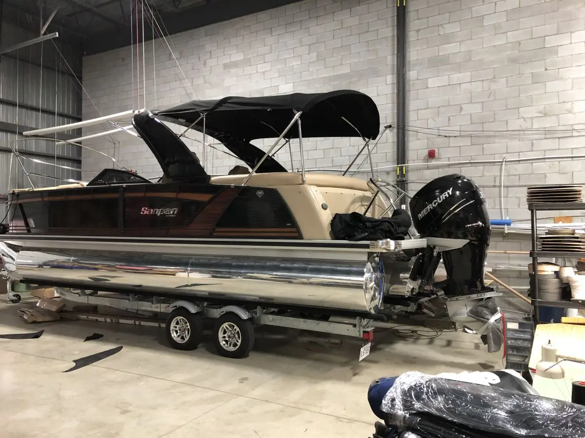 Bateau ponton dans un atelier Redecor Plus, muni d’un toit noir sur structure métallique