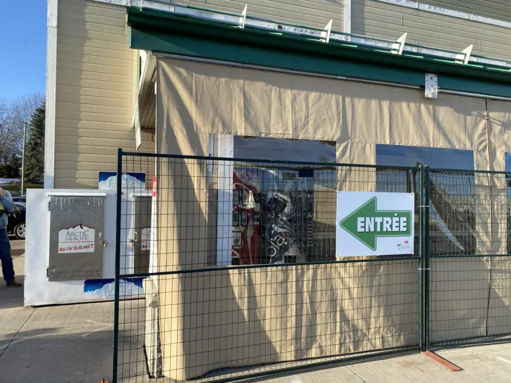 Abri extérieur fermé avec panneaux translucides et toile beige, idéal pour zones d’attente ou de repos