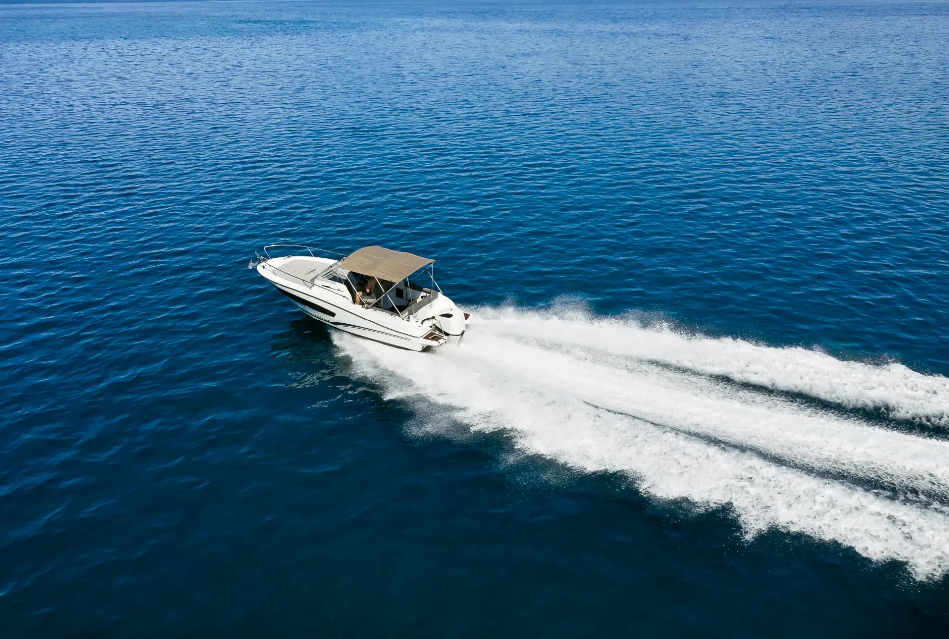 Bateau à moteur avec toile sur mesure beige naviguant à vive allure sur une mer calme