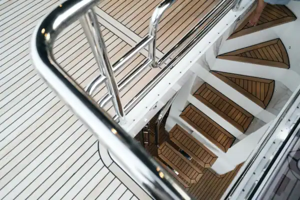 Revêtement de plancher marin en bois synthétique sur un bateau de luxe, incluant des escaliers et des surfaces antidérapantes.