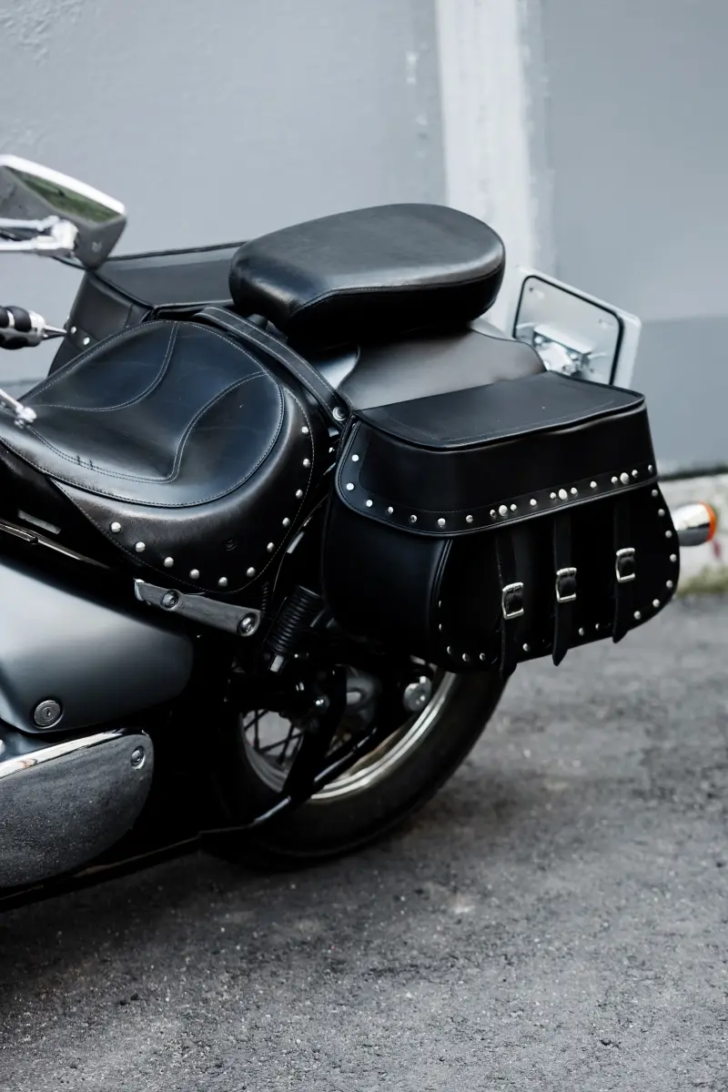 Détail d’une selle de moto noire sur mesure avec sacoches assorties, finition haut de gamme et rivets décoratifs