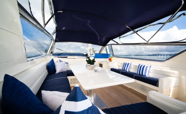 Coin détente d’un bateau avec toit bimini, table blanche et coussins marins sur mesure dans un aménagement haut de gamme